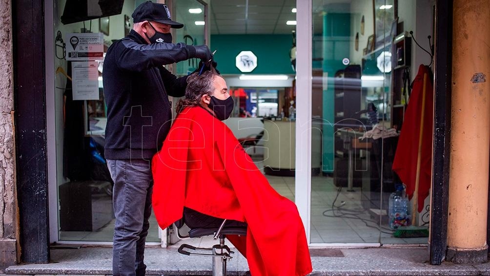 Un peluquero sacó el sillón a la vereda para atender a sus clientes